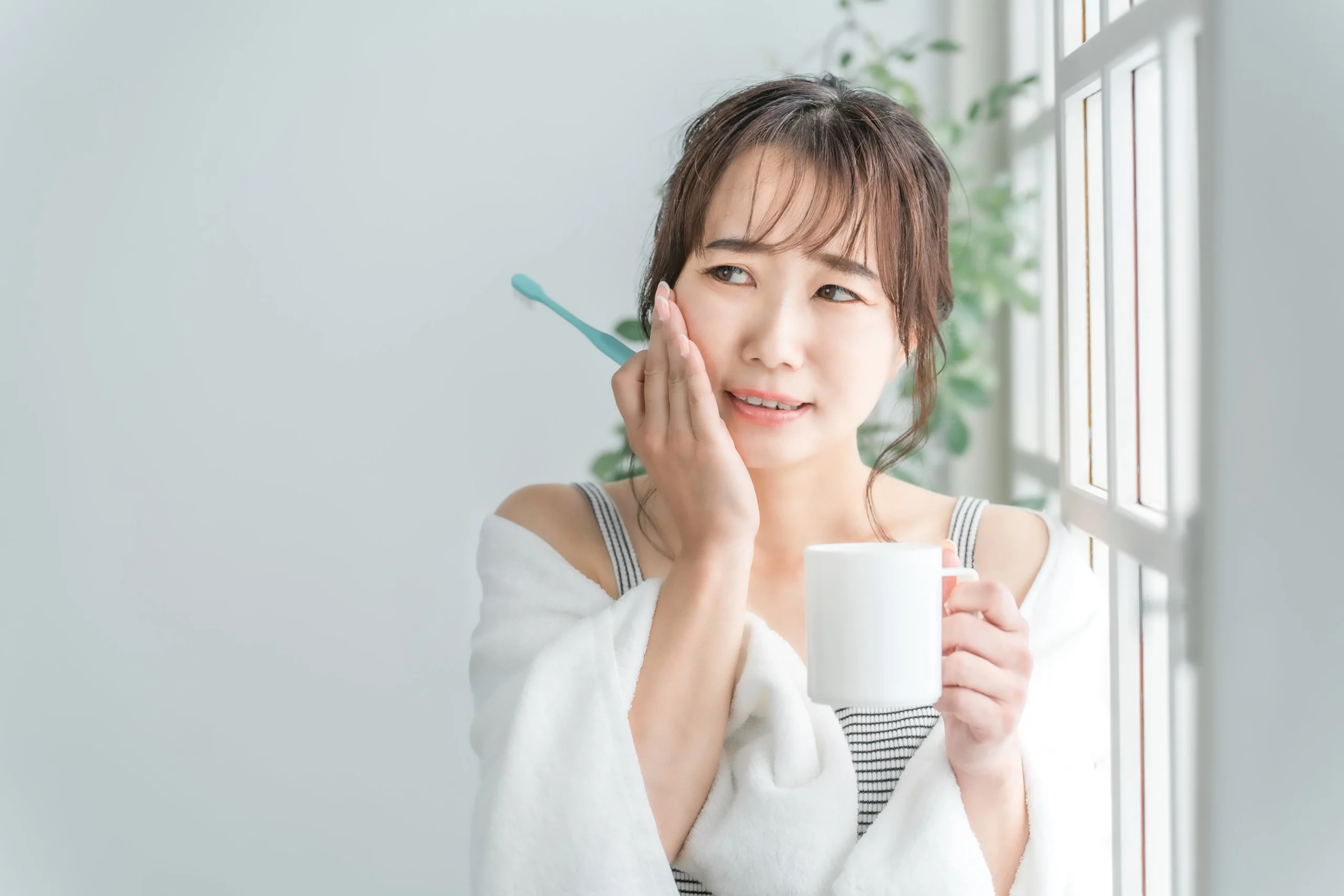 A woman holding her cheek while wincing in pain