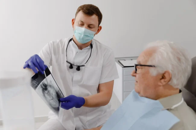 Desntist with a patient A dentist shows his patient an x-ray