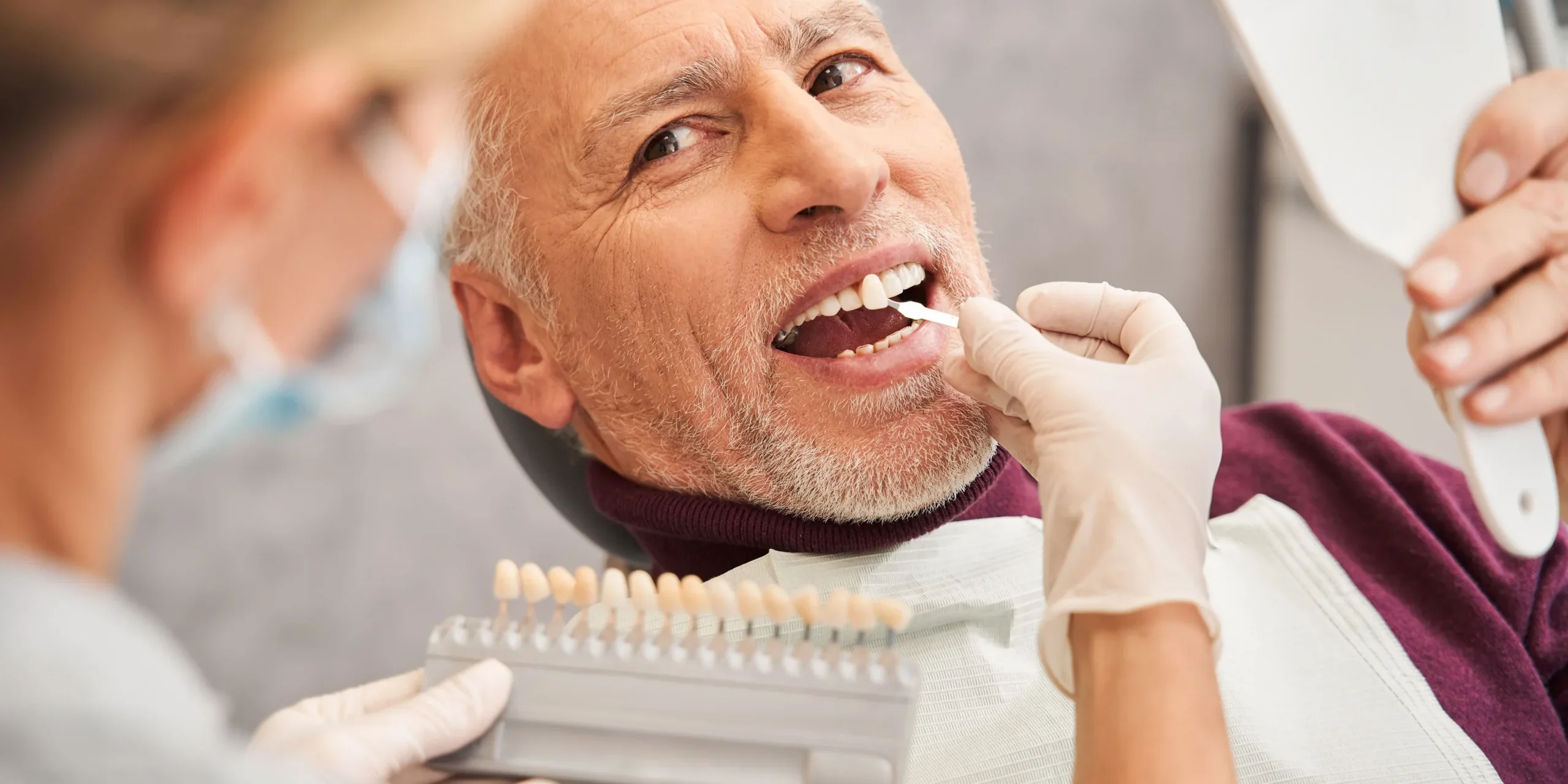 A dentist matches a patient's teeth colour on a whitening chart