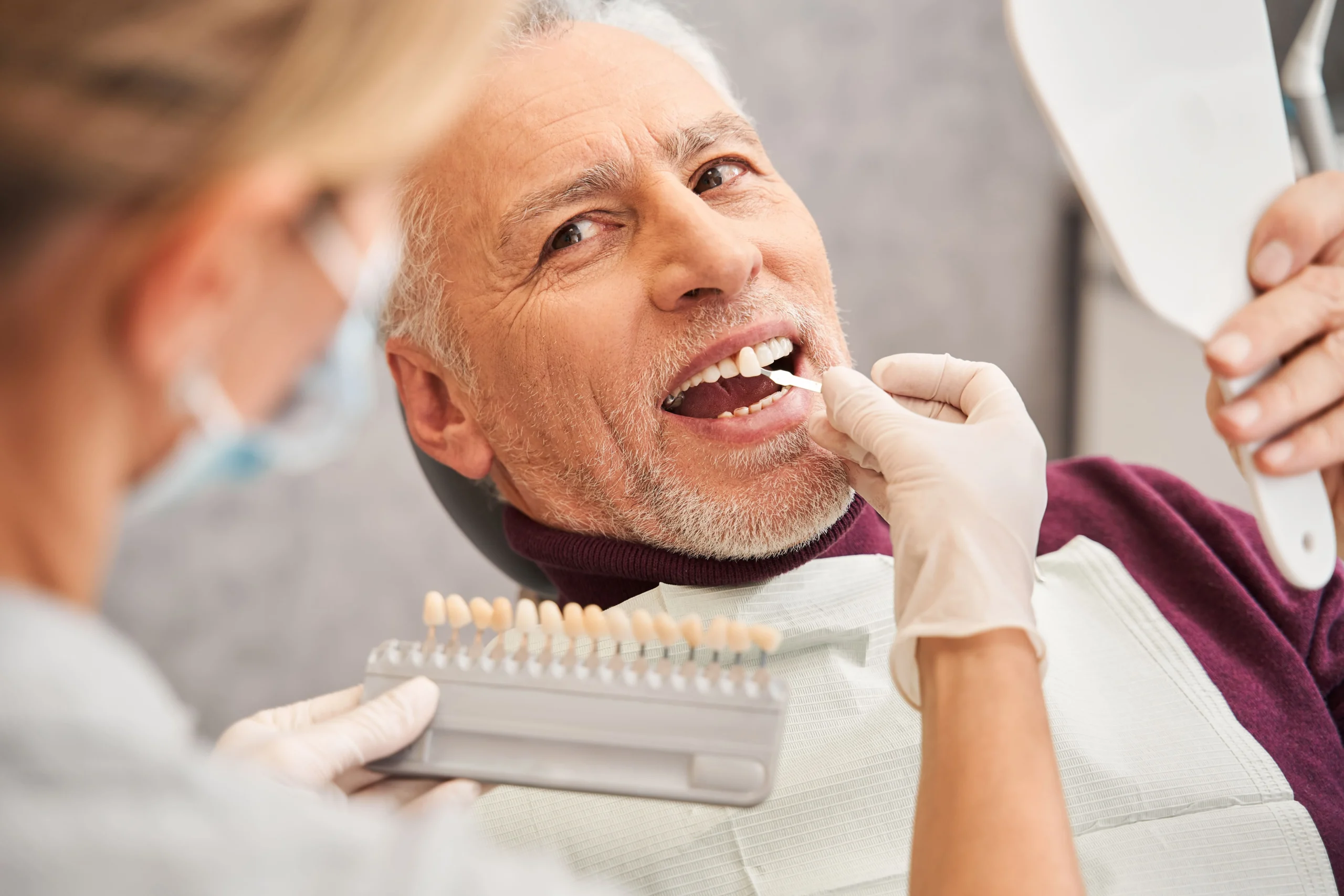 A dentist matches a patient's teeth colour on a whitening chart