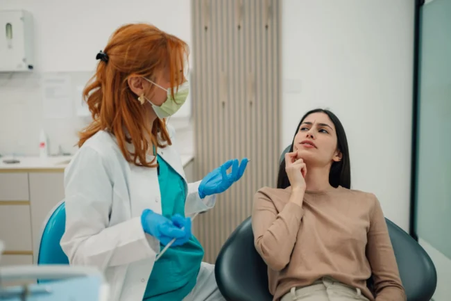 Dentist with a patient A dentist at a consultation with a female patient that seems to have a tooth ache