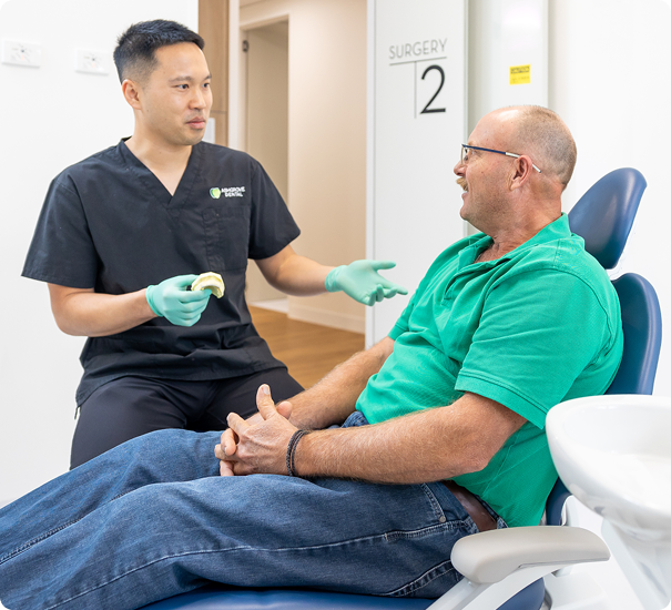 a dentist talking with a patient sitting on the clinic chair
